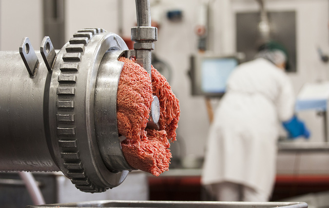 Kött kommer ut ur köttkvarn i fabrik