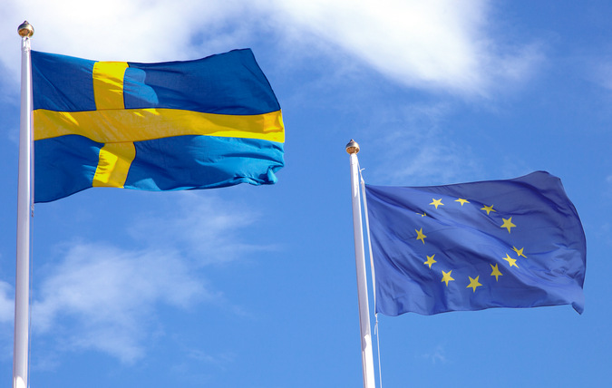En svenska och en EU flagga mot en blå himmel.