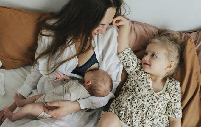 Woman breastfeeding with child next to her