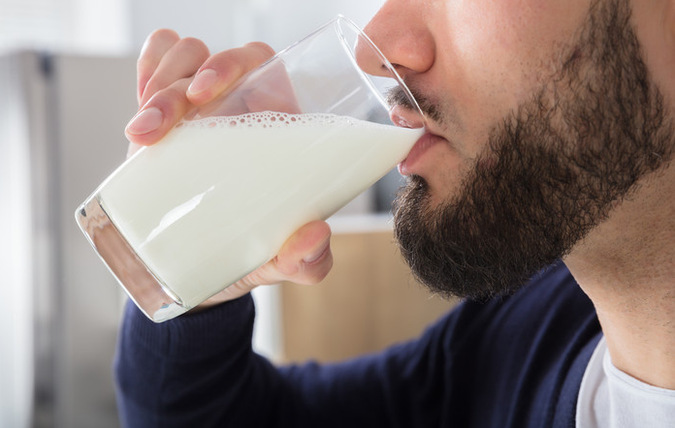 Närbild på man i profil som dricker glas med mjölk.