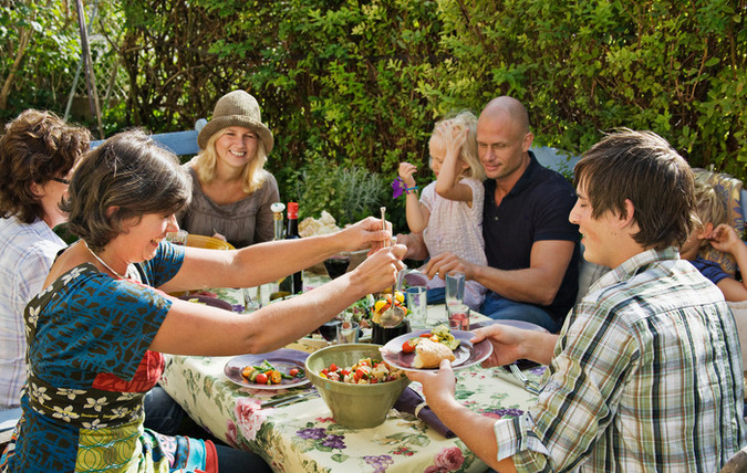 En grupp med människor i olika åldrar som äter mat på veranda