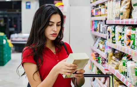 En kvinna som läser innehållsförteckningen på ett livsmedel i en butik.