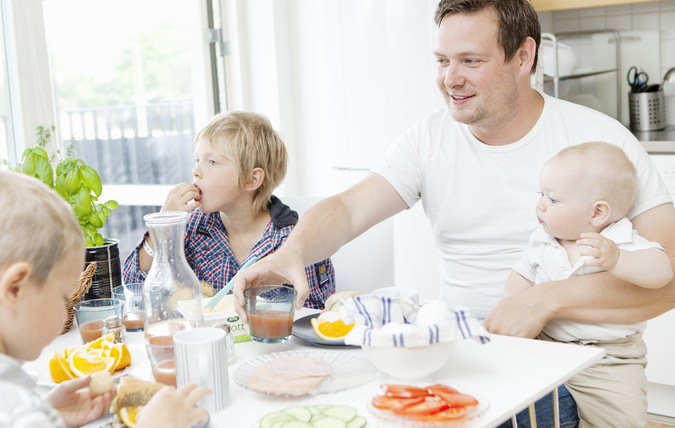 Familj som sitter och äter frukost vid ett köksbord