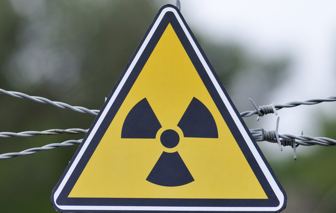 Närbild på varningstriangel med symbol för radioaktivitet.