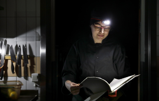 Kvinna läser ur pärm med hjälp av pannlampa i mörker
