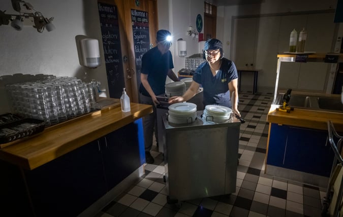 Måltidspersonal förbereder i skolmatsal under elavbrott.