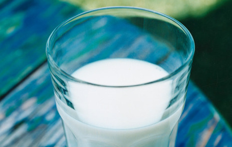 Ett glas med mjölk på ett blått trädgårdsbord
