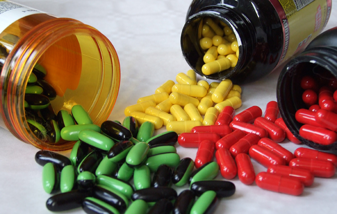 Three cans containing pills and pills spread around on a table