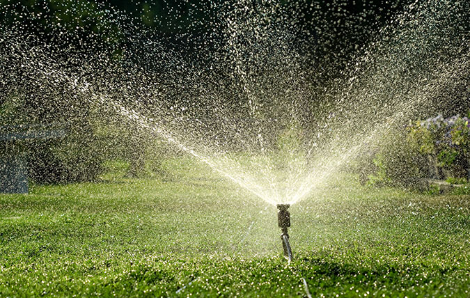 Vattenspridare som sprutar vatten på en gräsmatta