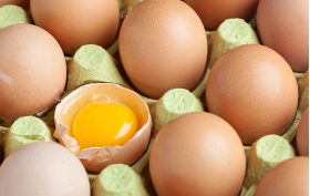 Förpackning med ägg - ett av äggen är knäckt och man ser den råa gulan