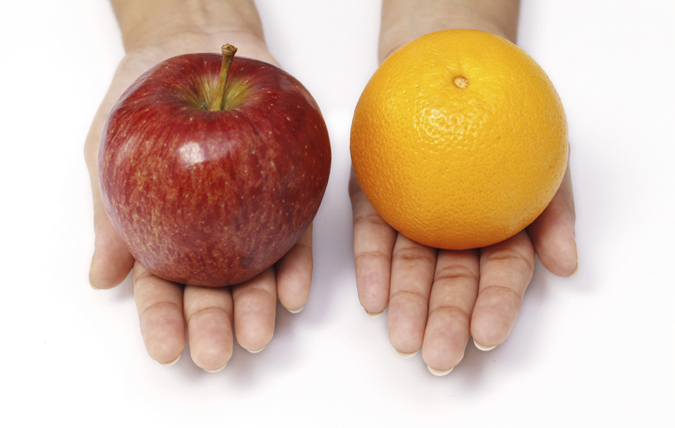 Händer som håller ett äpple och en apelsin