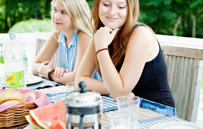 Två kvinnor vid ett frukostbord utomhus.