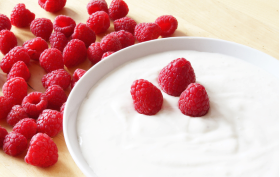 Tallrik med fil eller yoghurt med färska hallon i och bredvid