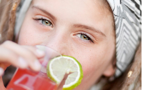 Ung kvinna dricker röd dryck ur glas