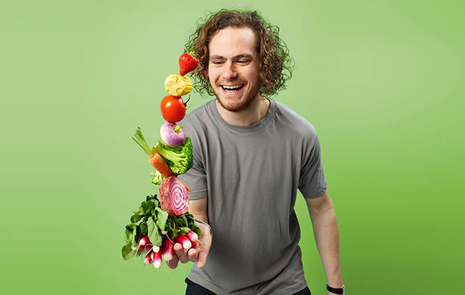 Skäggig man jonglerar med grönsaker